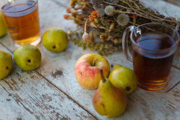 autumn harvest composition with apples pears cup of tea and dry healing herbs