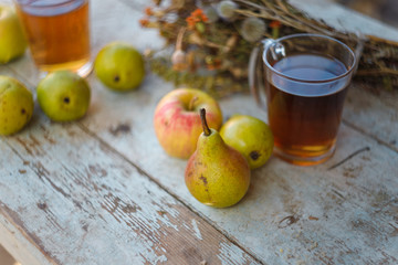 autumn harvest composition with apples pears cup of tea and dry healing herbs