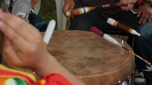 Native American men in a drum group hit drum at pow wow