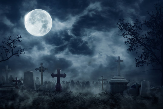 Zombie Rising Out Of A Graveyard cemetery In Spooky dark Night full moon. Holiday event halloween background concept.