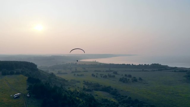 A person is flying above the fields on the parafoil