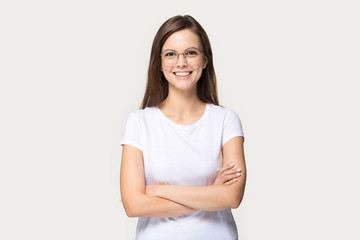 Smiling millennial girl in glasses standing with arms closed