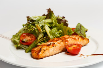salmon steak with vegetables on a white plate