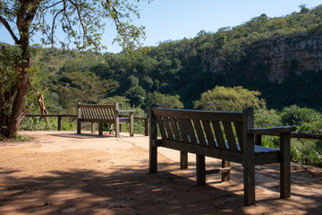 A bench overlooking the cliffs and dense vegetation along an African river.