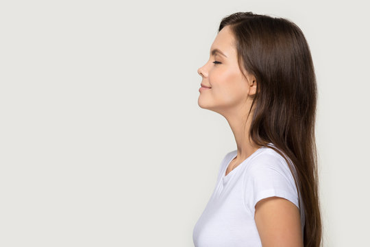 Peaceful millennial girl in profile stand near blank copy space
