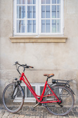 Fototapeta na wymiar red vintage bicycle parked on stone wall with a window