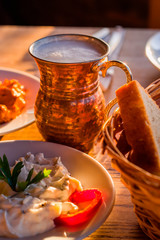 traditional turkish appetizers on table in evening sun light and ayran in a copper glass