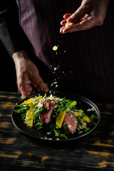 Cooking food fresh diet keto salad with beef meat and fruits on black background.