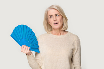 Overheated senior lady cooling herself using waver