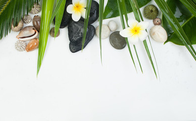 Palm leaves, tropical flower, candle and black and white stones on white background, top view, copy space. Spa concept