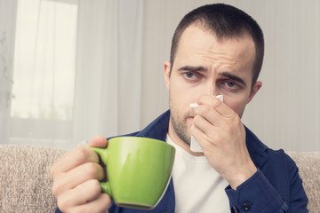 Man caught a cold, a male is at home on sick leave, man drinks the medicine and blew his nose,...