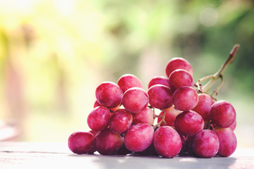 Bunches of ripe red grape on wooden wooden texture, natural green background