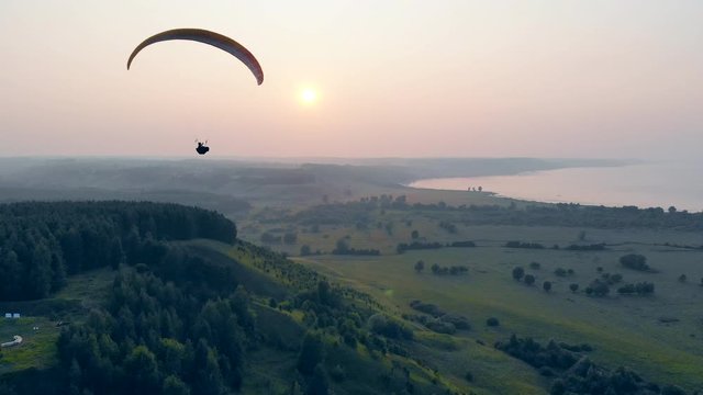 Sunset landscape and a person flying the paraplane