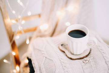 Top view of cup of coffee with a knitted beige plaid on background. Autumn and winter, leisure concept. Flat lay