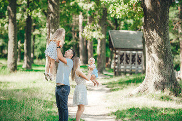 Father, mother and two daughters walking in the park. Friendly family.
