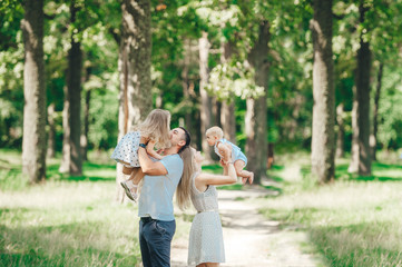 Young happy family spending time at park. Father kiss baby child.