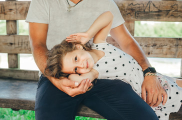 Cute little girl lying on her dad 's knees in summer house in garden
