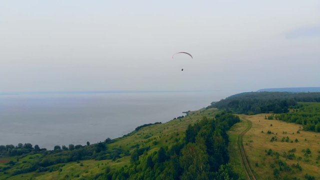 Waterscape with green hills and the paraglider flying over them
