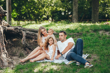 Family with children enjoying picnic in summer forest.