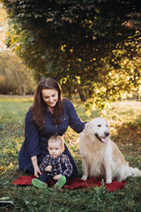 Mother,babyboy and a golden retriever in a beautiful autumn park