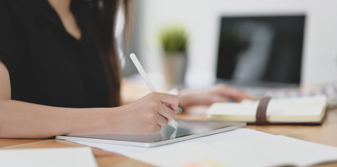 Close-up view of young female designer editing her concept with tablet