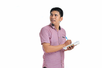 Asian male writing on his notebook look at blank area or copy space with pink t-shirt