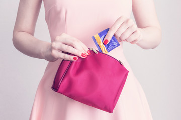  Girl with condom, woman puts condom in cosmetic bag, close up, toned, cropped image, the concept...