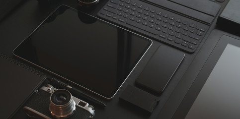 Black stylish workplace with tablet, smartphone, camera and office supplies