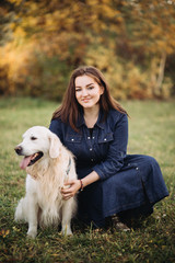 Young woman with a golden retriever in a beautiful autumn park