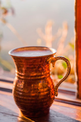 Ayran in a copper glass on table in evening sun light