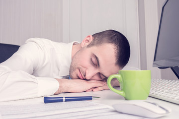 Businessman fell asleep at work, documents on his desk, toned