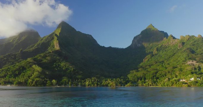 Aerial drone shot of lush green island with mountain peaks and a pristine blue lagoon in the foreground