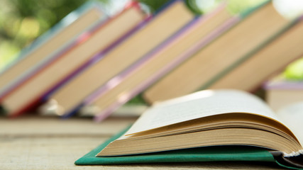 Open book on a wooden table in a garden. Sunny summer day, reading in a vacation concept