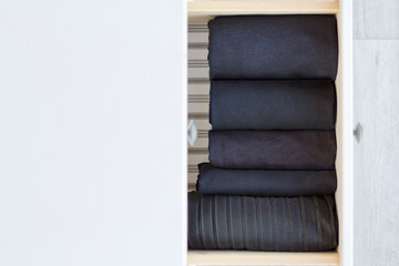 black clothes neatly folded vertically in an extended chest of drawers, top view