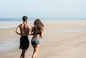pretty young couple jogging on the sunny beach