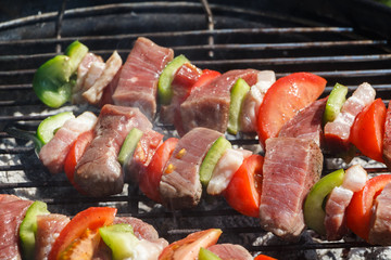 Beef brochettes grilling on the grid of a barbecue