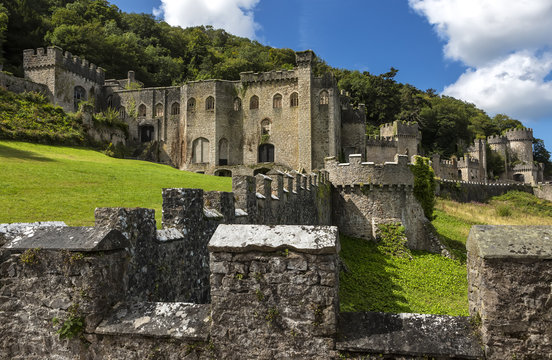 Gwrych castle in Wales UK surrounded by trees and foliage on hill side ruins.