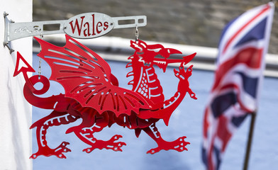 Tenby, Pembrokeshire / Wales UK - 20/8/2019:  traditional red dragon sign hanging from wall.