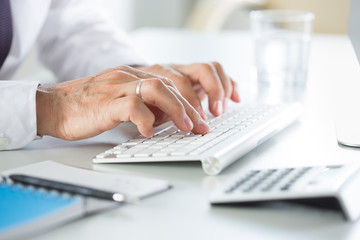 Fototapeta premium Close-up of businessman hands typing on the keyboard in an office