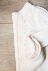 White knitted sweater on a wooden grey table, top view. Flat lay, copy space