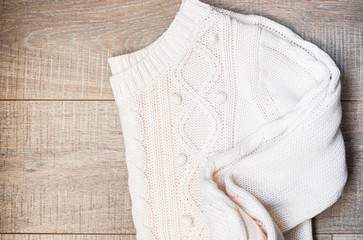 White knitted sweater on a wooden grey table, top view. Flat lay, copy space
