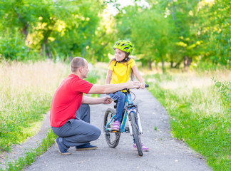 Obraz premium Father communicates with his daughter, teaching her how to ride a bicycle