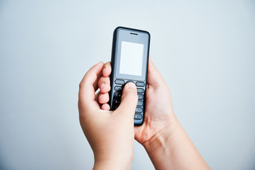 Child holding a traditional mobile phone on white backround