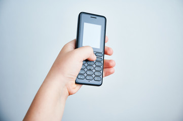 Child holding a traditional mobile phone on white backround
