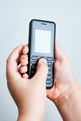 Fototapeta premium Child holding a traditional mobile phone on white backround
