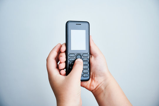 Child Holding A Traditional Mobile Phone On White Backround