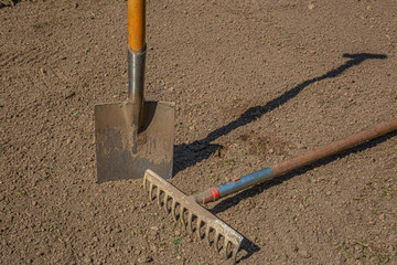 a spade and a rake on finished garden mold