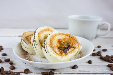 Cup of coffee on a white wooden table and a cake