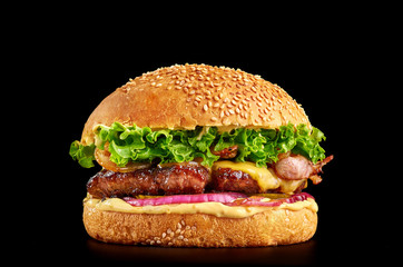 burger at black background with beef or pork cutlet or steak with onion, cheese, bacon, lettuce and mustard sauce in white bun with sesame