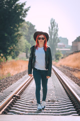 The girl walk by railway alone. Beginning of a long lonely journey. Hard way over sharp stones between. Woman continues to move forward. summer sunny day, cowboy hat and Sunglasses